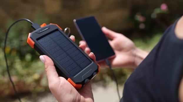 Mobile phone and solar power bank in hands closeup. Modern energy saving devices for recharging devices concept