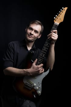 A man with an electric guitar looks at the camera.