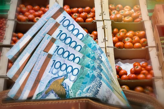 Rising prices for vegetables and agricultural products in Kazakhstan. Tenge in a wallet against the background of a counter with tomatoes.