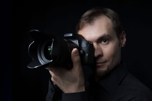 Close-up portrait of a professional photographer with a camera in the dark like a paparazzi.