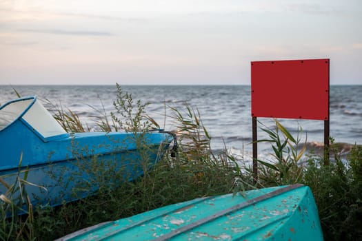 old boats at sunset on the seashore. a red warning sign with a place for text.