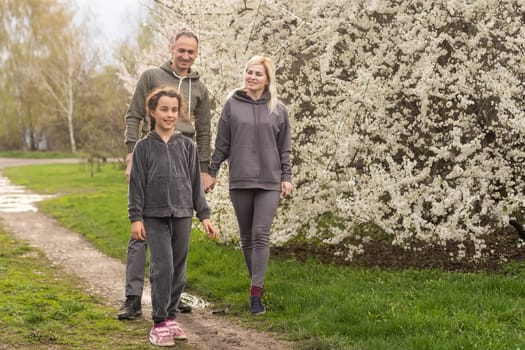 Young parents with daugther walking outside in spring nature