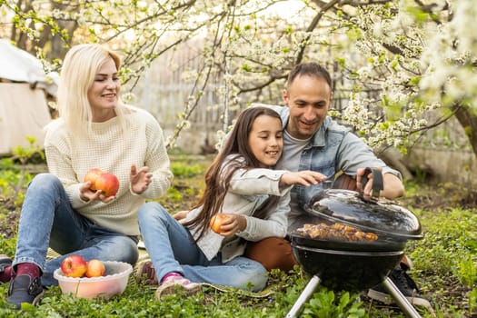 Happy family having a barbecue in their garden in spring. Leisure, food, family and holidays concept