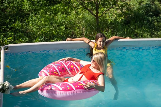 Beautiful woman with her daughter in swimming pool.