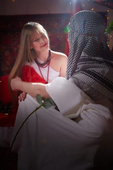 Portrait of young arabian muslim couple in traditional clothes in cozy red room. Fhoto shoot in easten style with male and female model like in harem with a sultan and an odalisque. Partial focus