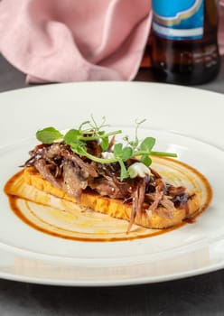 Beef bruschetta on a white porcelain plate on a dark gray table