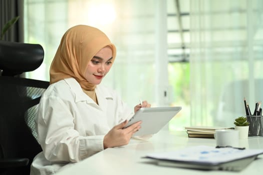 Portrait of elegant muslim woman corporate CEO checking her working plan on digital tablet at her workplace.