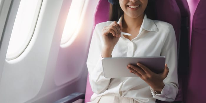 Beautiful Asian businesswoman working with digital tablet in aeroplane. working, travel, business concept.