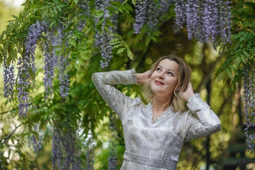 Wisteria woman. Thoughtful happy mature woman surrounded by chinese wisteria.