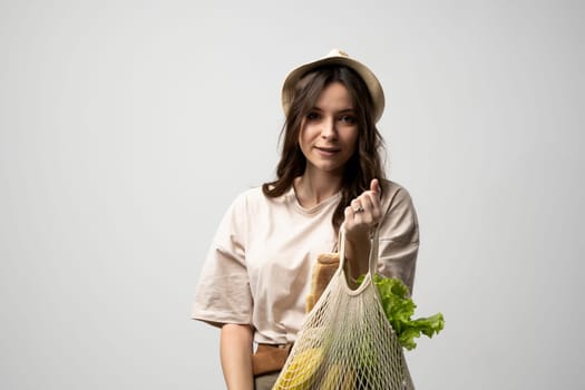 Girl is holding mesh shopping bag with vegetables, greens without plastic bags. Zero waste, plastic free. Eco friendly concept. Sustainable lifestyle