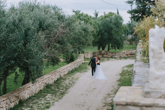 Happy stylish smiling couple walking in Tuscany, Italy on their wedding day. The bride and groom walk down the street by the hands. A stylish young couple walks. Husband and wife communicate nicely. Lovers run through the streets of the city.