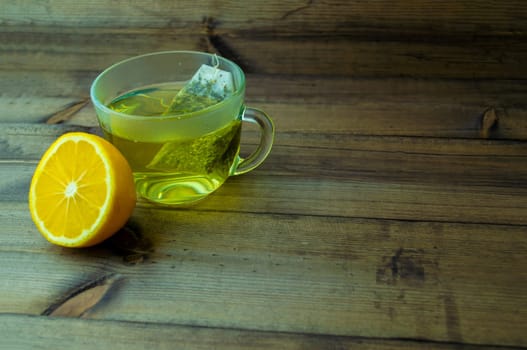 Green tea with lemon. Green tea in a glass mug and lemon on a wooden table.