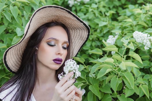 A fashionable girl with dark hair, a spring portrait in lilac tones in summer. Bright professional makeup