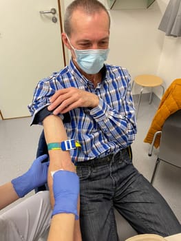 a nurse, doctor or medical technologist in blue gloves taking a blood sample from a patient in a hospital. High quality photo