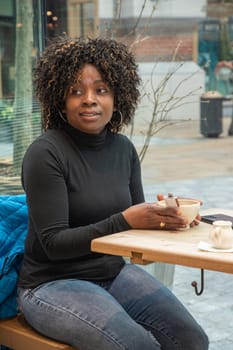 African american woman without makeup sits in a cafe in the morning, having just woken up, and drinks coffee, High quality photo