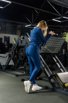 Photo of sporty caucasian woman poses in a gym . wearing blue leggins and long sleeve top