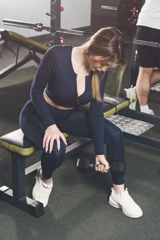 Woman doing biceps curl with dumbbells in seated position. white sneakers