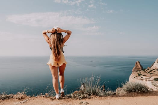 Woman travel sea. Happy tourist taking picture outdoors for memories. Woman traveler looks at the edge of the cliff on the sea bay of mountains, sharing travel adventure journey.