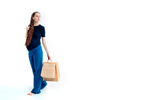 Shopping concept: Young pregnant woman with shopping bags full length portrait on white background.