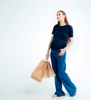 Shopping concept: Young pregnant woman with shopping bags full length portrait on white background.