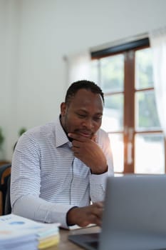 middle aged man American African using computer laptop with planning working on financial document, tax, exchange, accounting and Financial advisor.