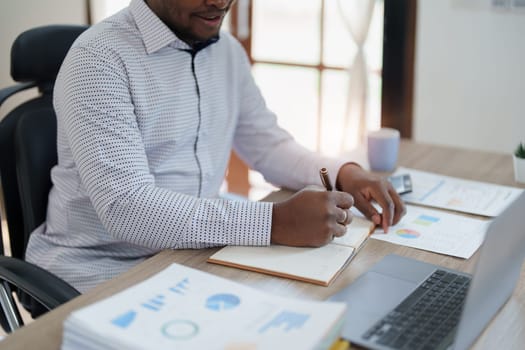 middle aged man American African using computer laptop with planning working on financial document, tax, exchange, accounting and Financial advisor.