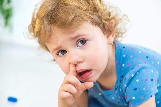 The child sticks his finger in his nose. Selective focus. Kid.