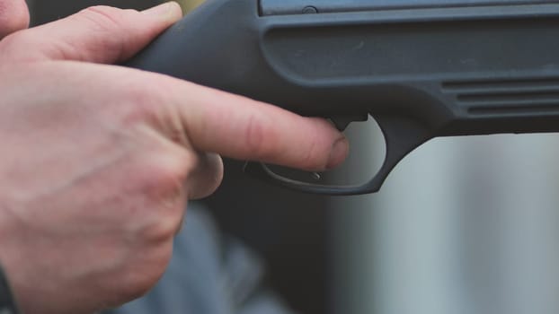 A man firing an air gun. Close-up of her hands