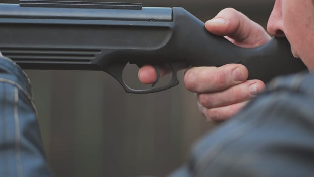A man firing an air gun. Close-up of her hands