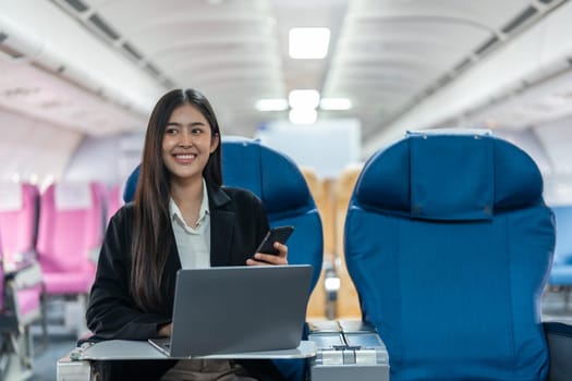 transport, tourism and technology concept of business woman with smartphone and laptop traveling by plane.