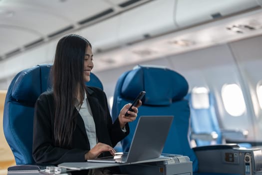 transport, tourism and technology concept of business woman with smartphone and laptop traveling by plane.