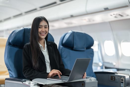 Female passenger sitting on plane while working on laptop computer with simulated space using on board wireless connection.