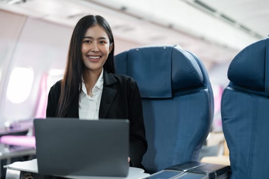 Female passenger sitting on plane while working on laptop computer with simulated space using on board wireless connection.