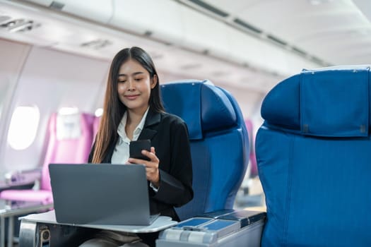 transport, tourism and technology concept of business woman with smartphone and laptop traveling by plane.