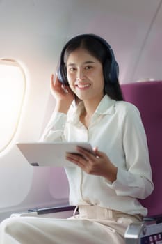 Beautiful Asian businesswoman working with digital tablet in aeroplane. working, travel, business concept.