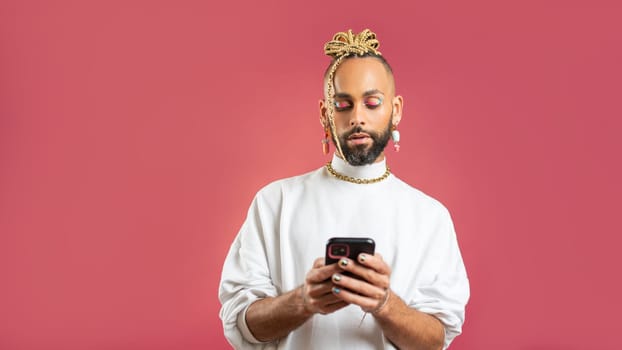 Trendy black latin gay man in white clothes use smartphone looking device screen on pink background studio portrait People lifestyle fashion lgbtq concept