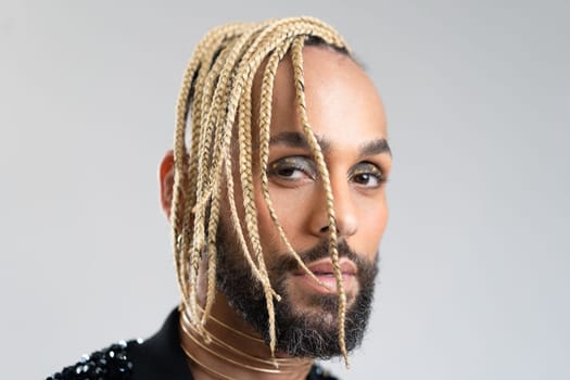 Afro-american homosexual male posing in photo studio on white background. Bearded gay with beard and make up close up portrait