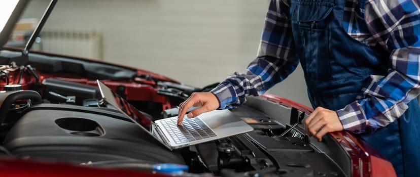 Woman auto mechanic doing engine diagnostics using laptop