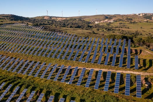 Long rows of photovoltaic panels at solar farm for converting energy of sun to electricity in concept of renewable energy and natural resources. Aerial view