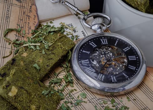 Bangkok,Thai - Mar 17, 2023 : The Analog Pocket Watch beside the Homemade Cannabis Snack Sticks and chopped cannabis leaves on the old vintage music notes. The Concept of Relaxation and the Happiness of the Music Lovers.