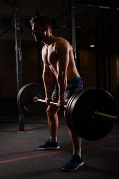 Shirtless caucasian man doing deadlift in the gym