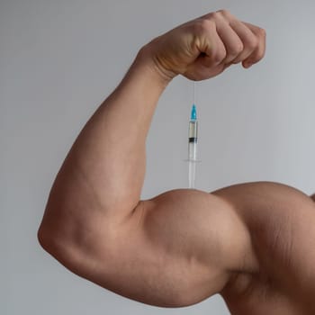 Closeup of a male hand with a dope syringe. Cropped biceps of a man. Unrecognizable bodybuilder sets himself growth hormone testosterone