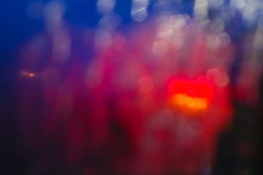 Raindrops and stains on glass at night in the city, blurred background