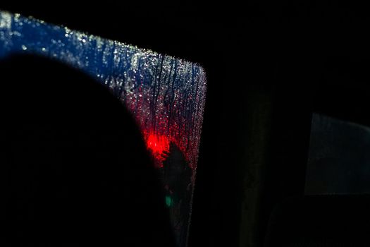 Side window of a car at night with raindrops close up