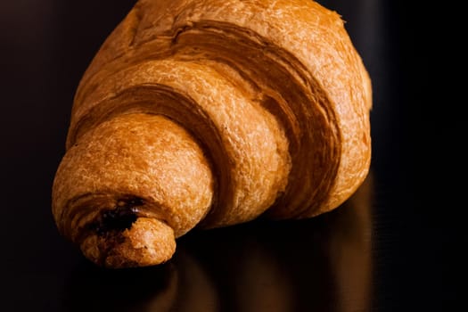 Croissant with chocolate on a black wooden table