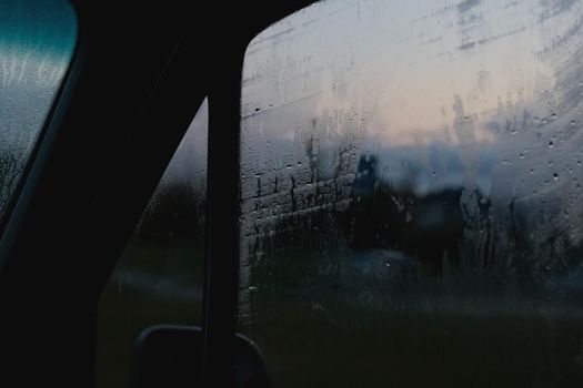 Side window of a car at night with raindrops close up