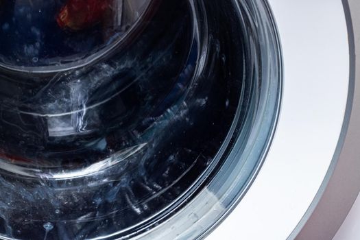 Dark laundry washing in machine drum close up, background