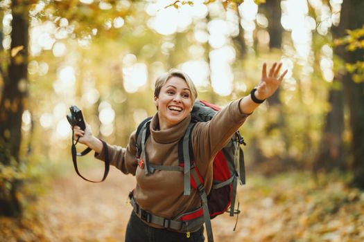 Shot of a mature woman to catch the hiking friends who chasing up during walk through the forest in autumn.