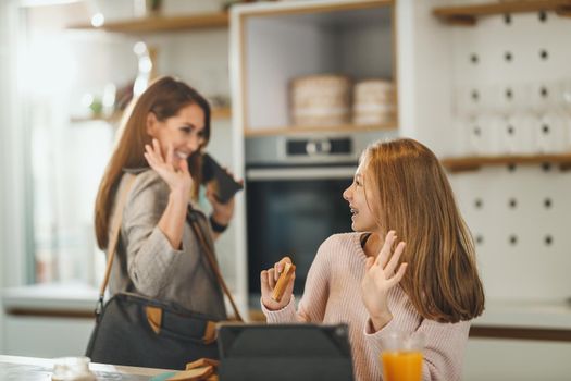 Shot of a cute teenage girl and her smiling mother is greet each other at her home while mom getting ready to go to work.