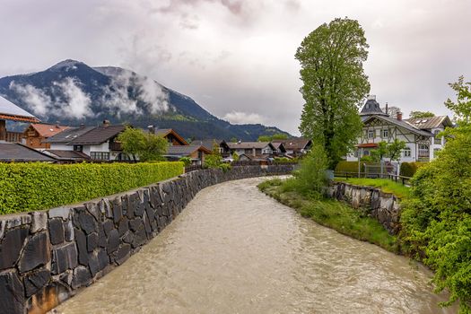 Garmisch-Partenkirchen, Bavaria, Germany, Loisach river flows through Garmisch-Partenkirchen, landscape of gloomy summer morning after rain, fog envelops mountain peaks.